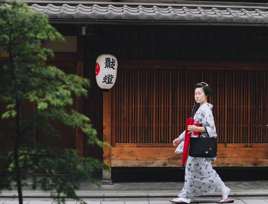 A geisha in a kimono walks along a traditional street in Kyoto, Japan.