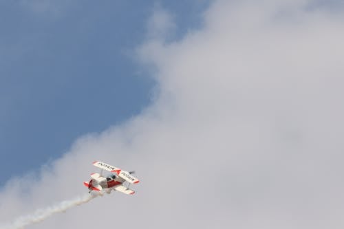 白曇りの日に飛んでいる白と赤の複葉機