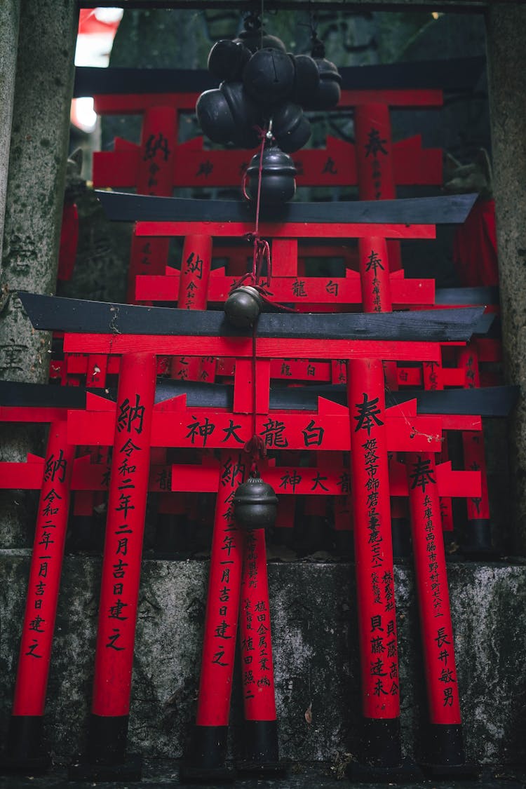 Red Wooden Torrii Gate Ornaments And Bells Hanging On Gray Concrete Wall