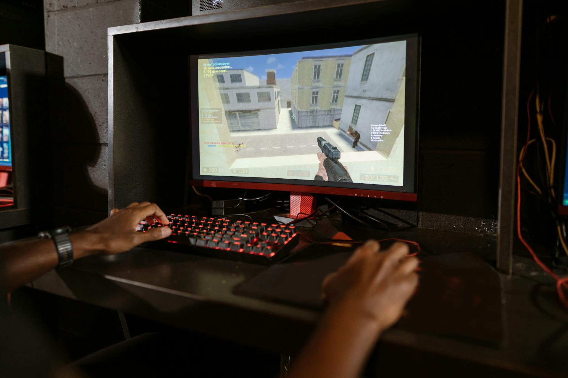 Person engaging in a shooting video game on a high-performance setup with mechanical keyboard.