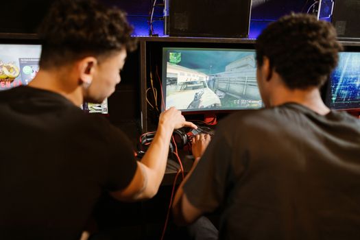 Two young men playing a multiplayer computer game at an arcade with enthusiasm and focus.