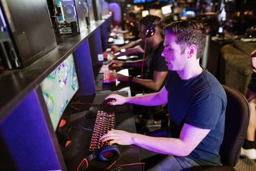 A group of men playing video games in an arcade with glowing gaming setups.