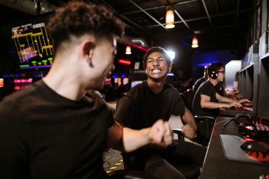 Group of gamers expressing excitement while playing video games in an arcade.