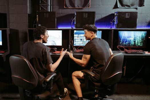 Two friends chatting while playing games in a modern internet cafe.