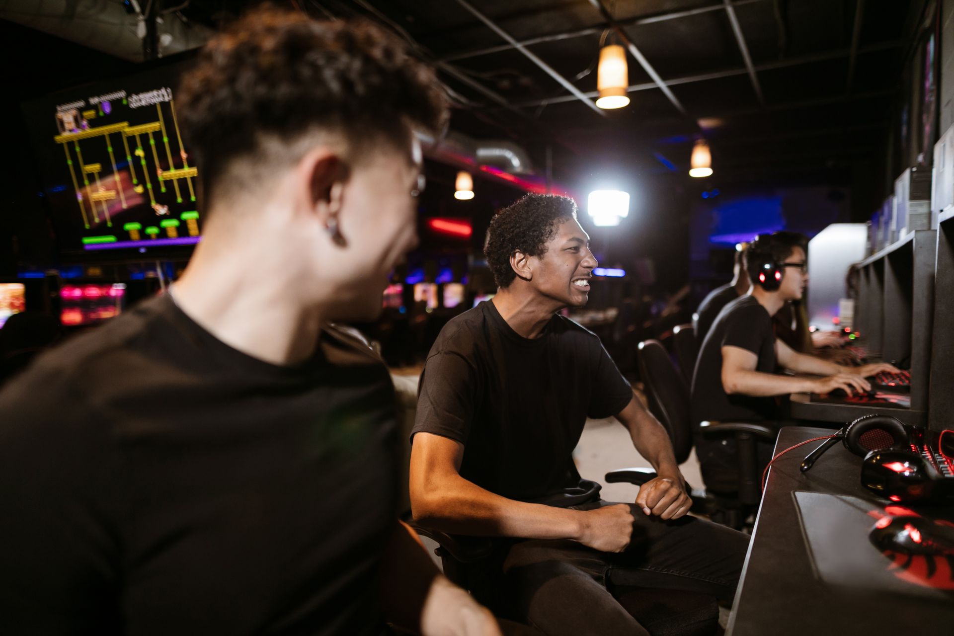 Group of friends enthusiastically playing video games in a modern arcade setting.