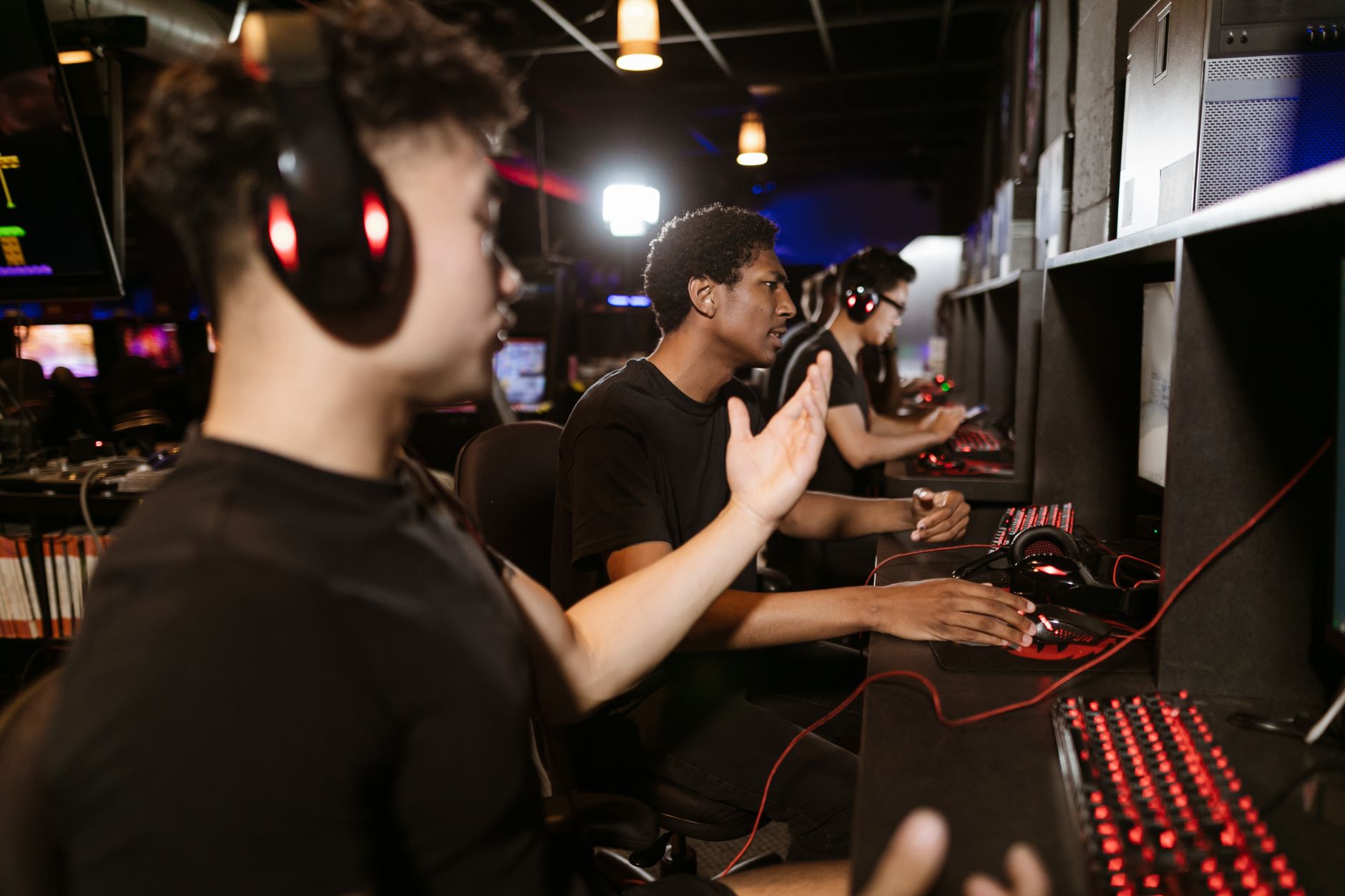 Energetic group of young adults engaging in PC gaming at an indoor cyber arcade.