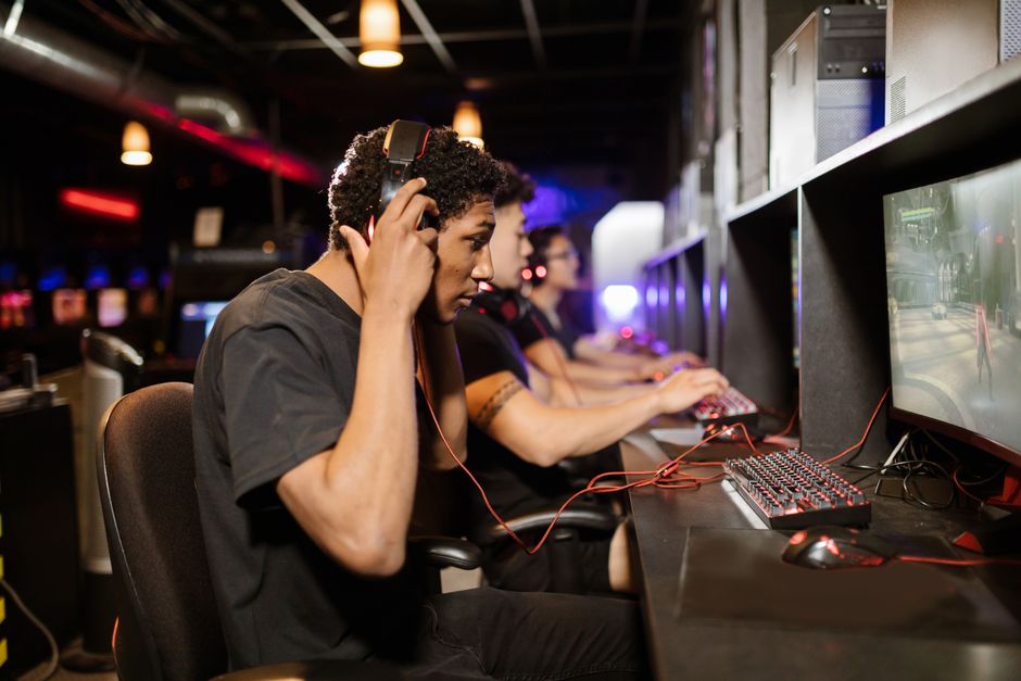 A group of young adults intensely focused on playing video games in a modern gaming lounge. A group of young adults intensely focused on playing video games in a modern gaming lounge.