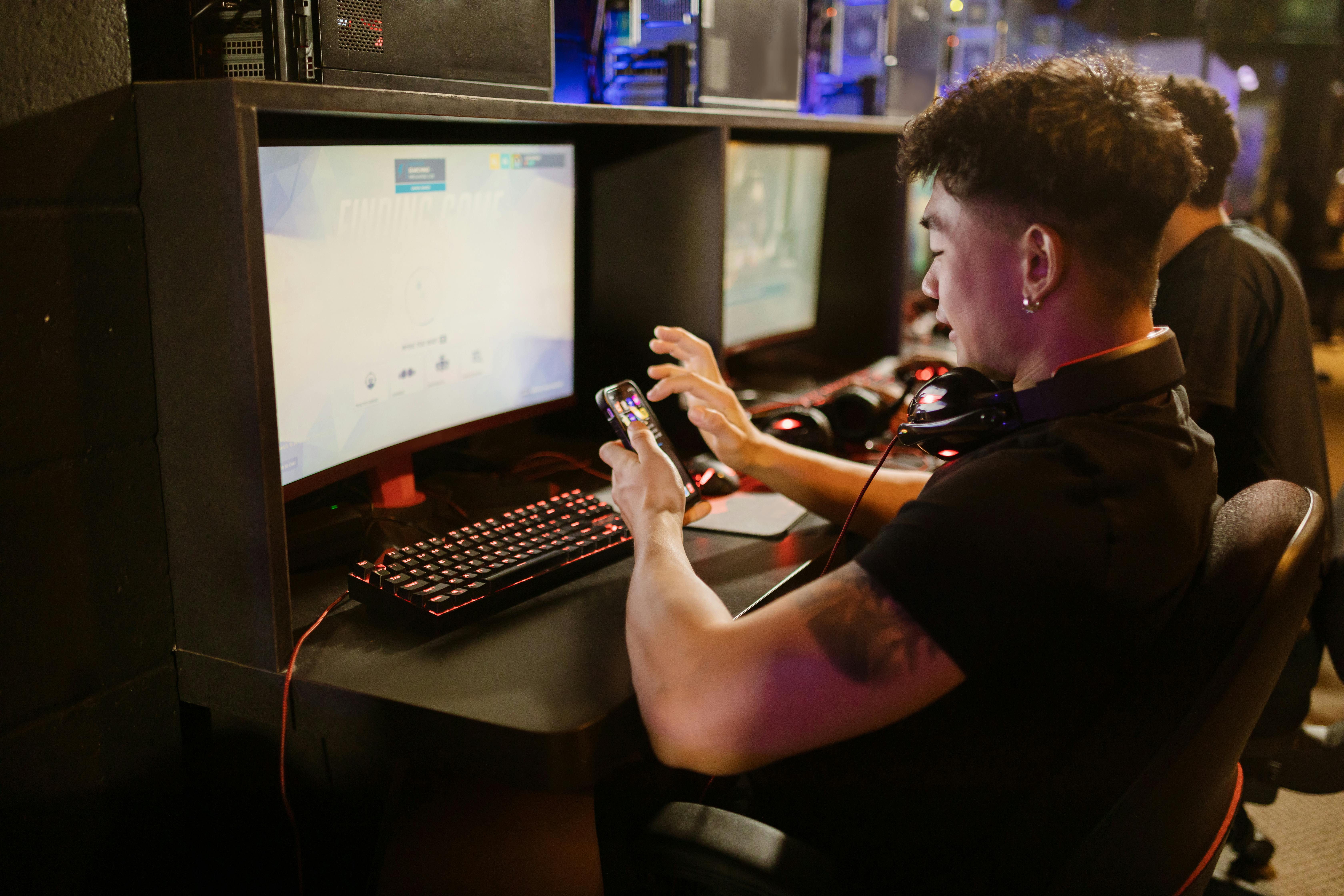 Man in Black Shirt Using a Smartphone while Sitting by the Gaming ...