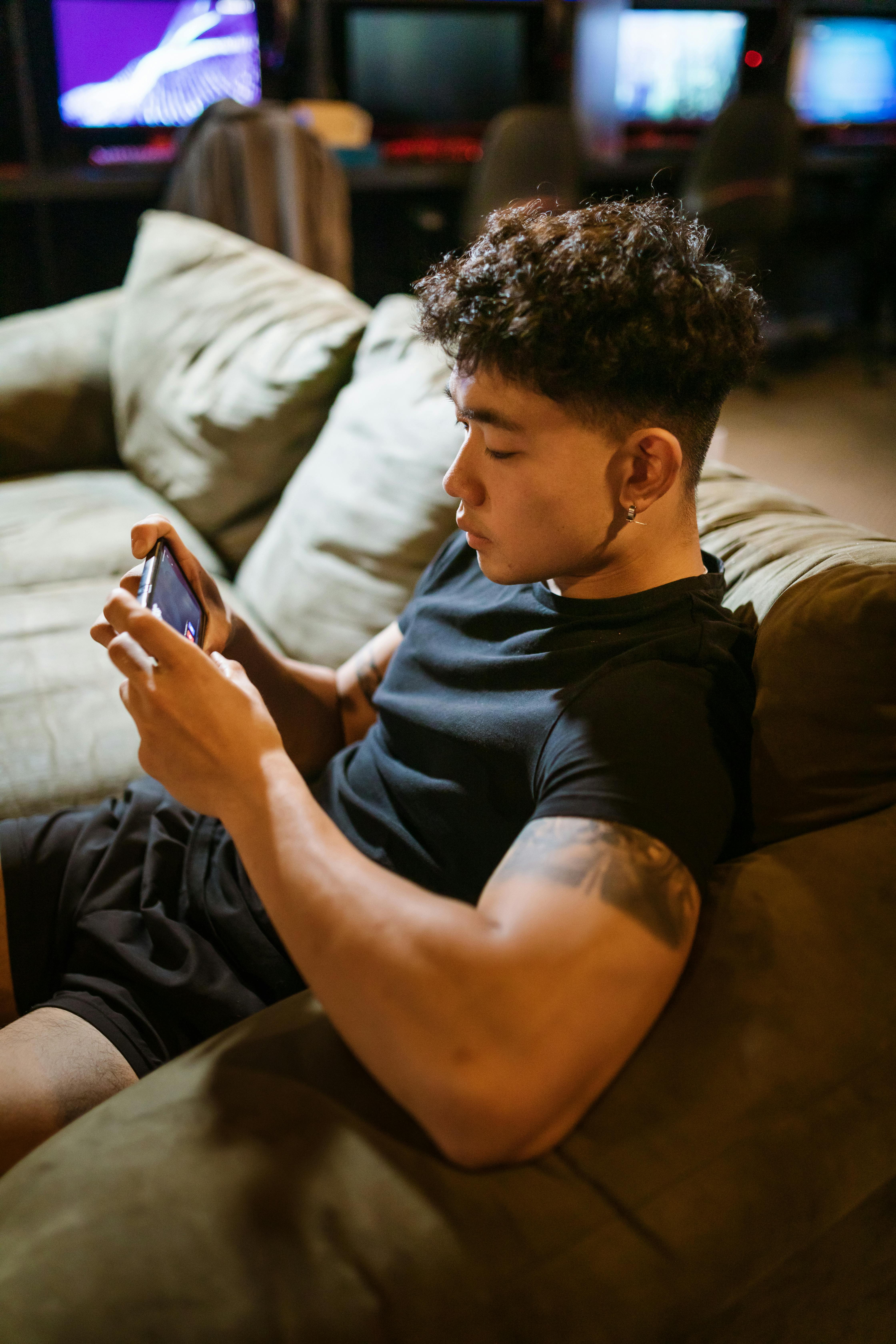 man in black crew neck t shirt playing mobile game