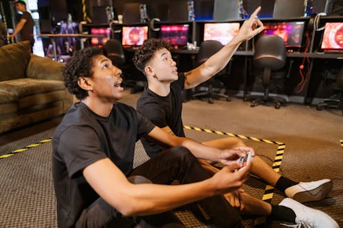 Two Men Sitting on the Floor while Playing a Video Game