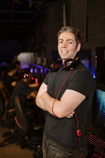 Smiling gamer with headphones in esports arena, exuding confidence and modern vibe.