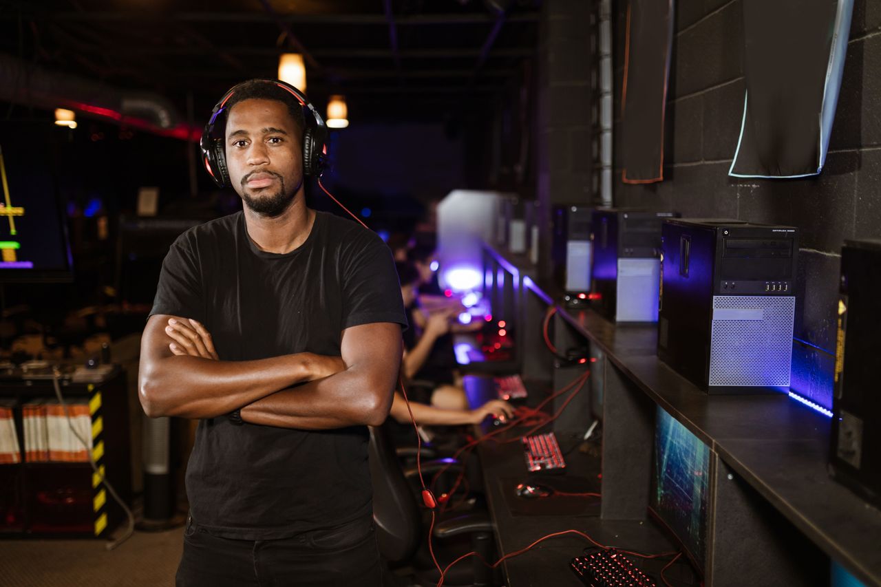 young man standing confidently in a modern esports arena with computer