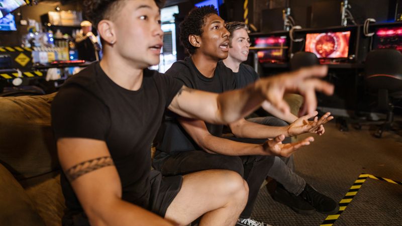 A diverse group of friends intensely playing video games in an arcade setting.