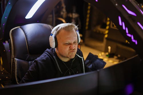 A Man Wearing White Headphones Playing a Computer Game
