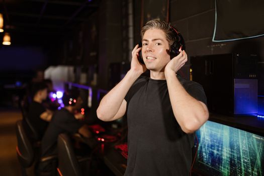 A man in a black shirt with headphones, enjoying gaming in a cyber cafe.