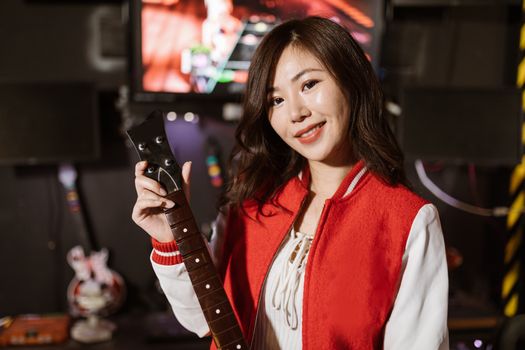 Young woman enjoying Guitar Hero game indoors, showcasing modern gaming and leisure activity.