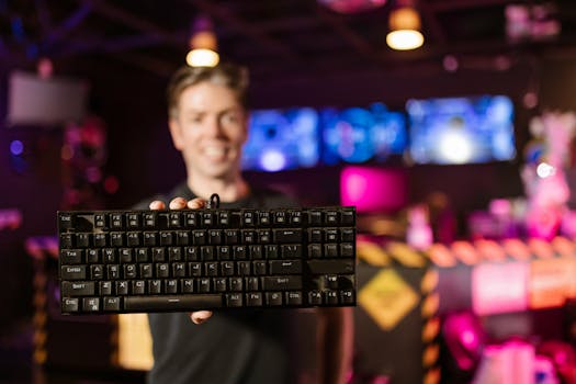 Blurred man holds up a mechanical keyboard in a vibrant gaming environment.
