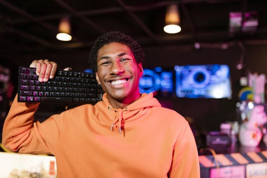 Smiling young gamer in an orange hoodie holding a keyboard in an exciting esports setting.