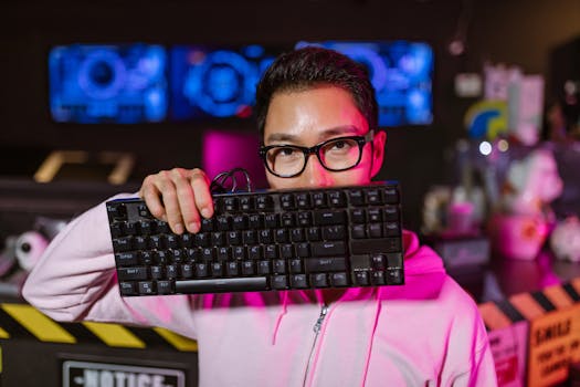 Gamer in pink hoodie posing with mechanical keyboard in a neon-lit gaming room.
