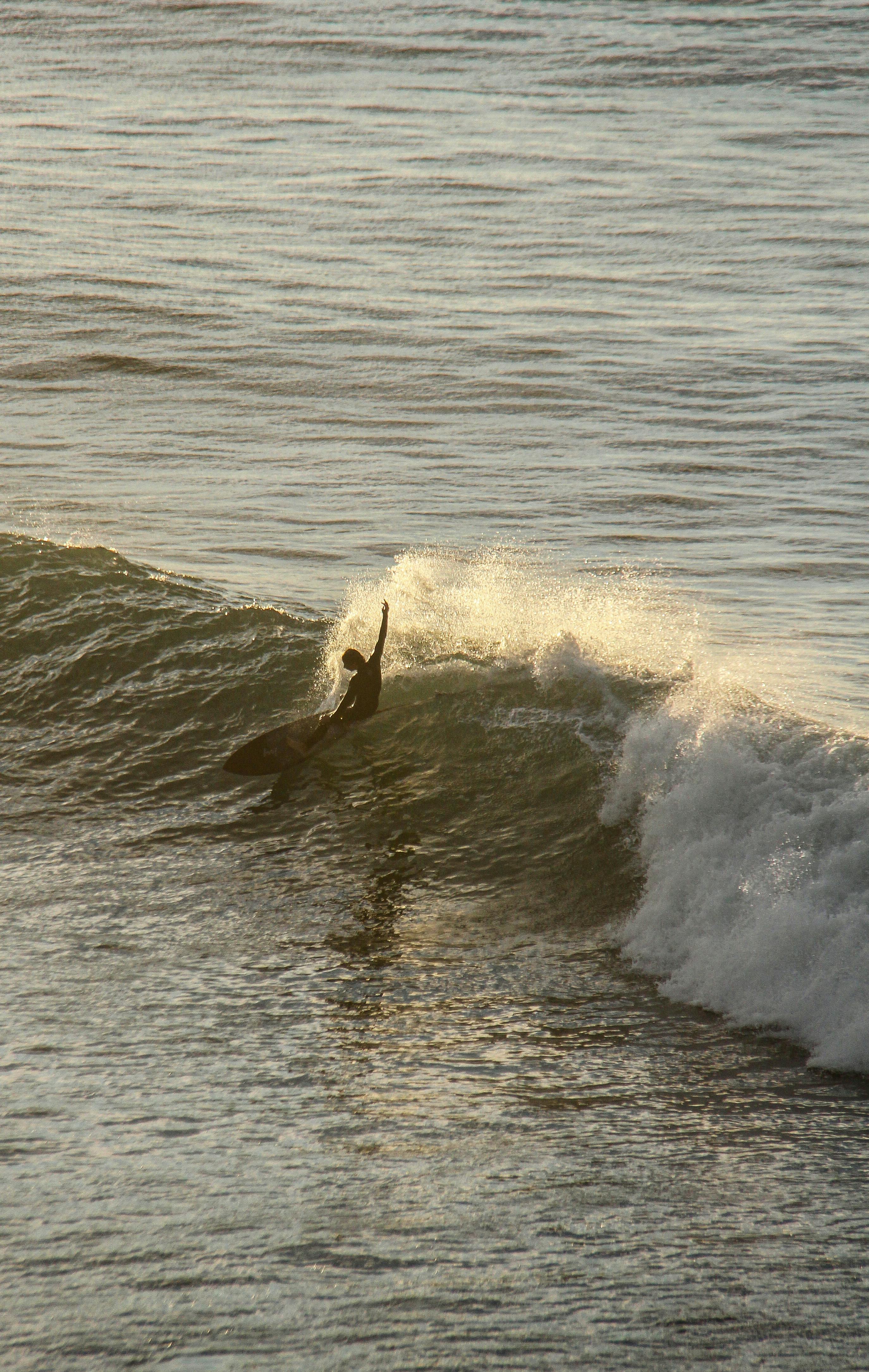 Experience the thrill of surfing at Bells Beach, Australia as a lone surfer rides a stunning wave.