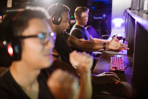 Free A group of diverse friends enjoying an intense gaming session in an indoor arcade setting. Stock Photo