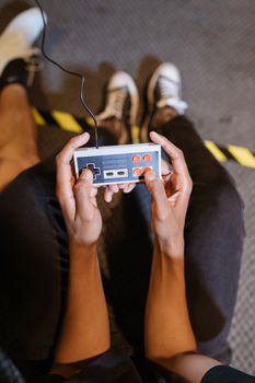 Person holding a vintage game controller, showcasing gaming focus and nostalgia.