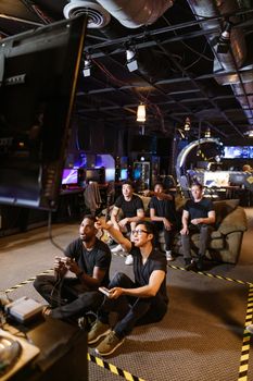 A diverse group of friends playing video games in a modern arcade setting.