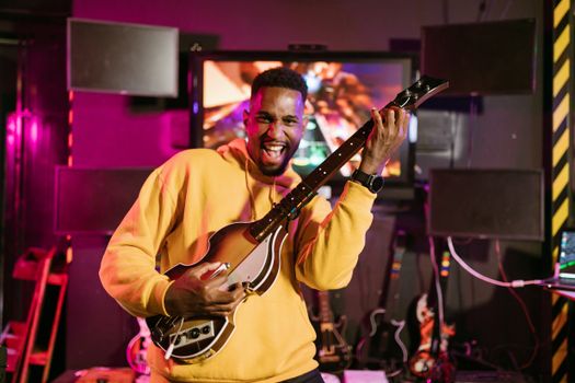 A cheerful adult playing Guitar Hero indoors, exuding excitement and happiness.