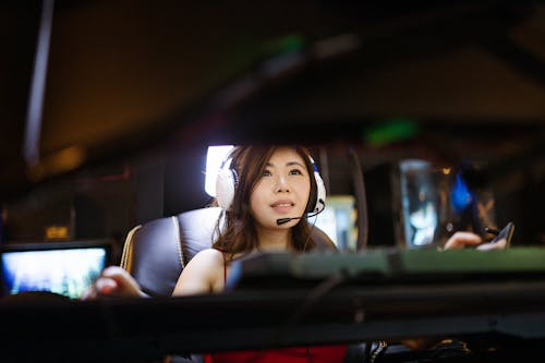 A Woman Wearing White Headphones Playing a Video Game