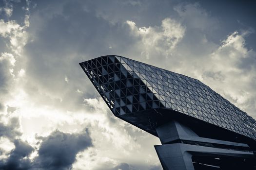Dramatic view of Antwerp's modern architectural landmark against a cloudy sky.
