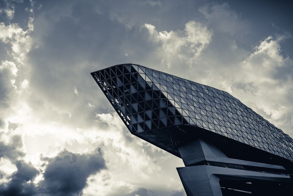 Dramatic view of Antwerp's modern architectural landmark against a cloudy sky.