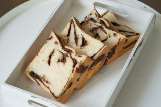 Freshly sliced chocolate swirl bread in a wooden tray, showcasing a delicious close-up view.