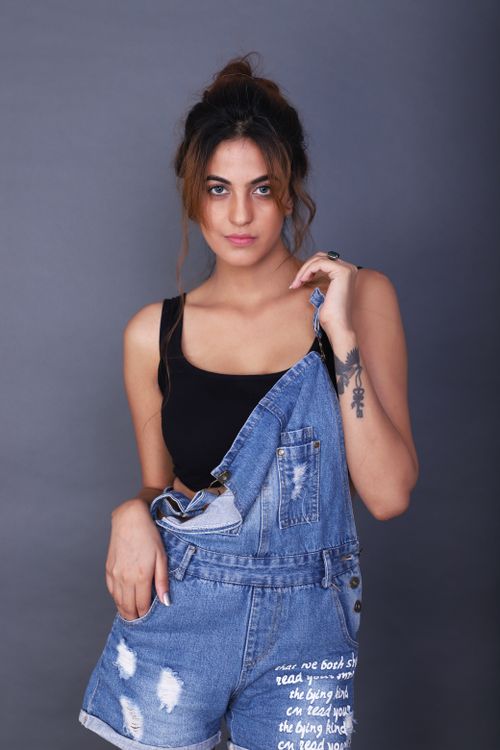 Free Fashionable woman posing in denim overalls against a gray background. Stock Photo