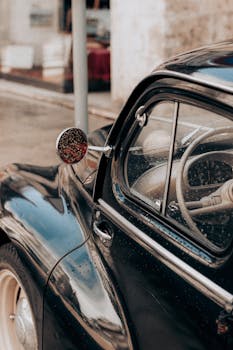 Detail of a classic vintage car with raindrops on the window and shiny exterior, showcasing retro elegance.