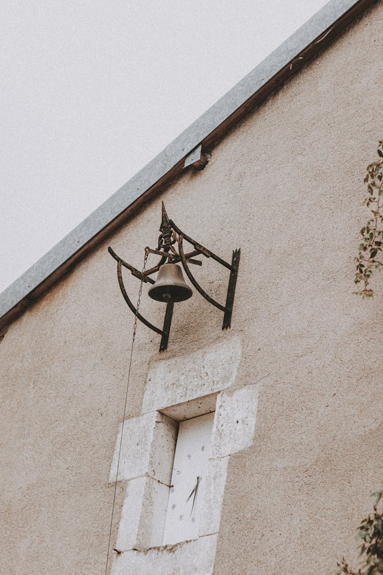 A Bronze Bell Hanging On A Concrete Wall