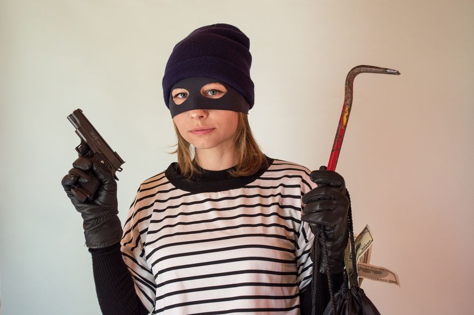 A woman dressed as a robber holding a gun and crowbar, implying criminal activity.