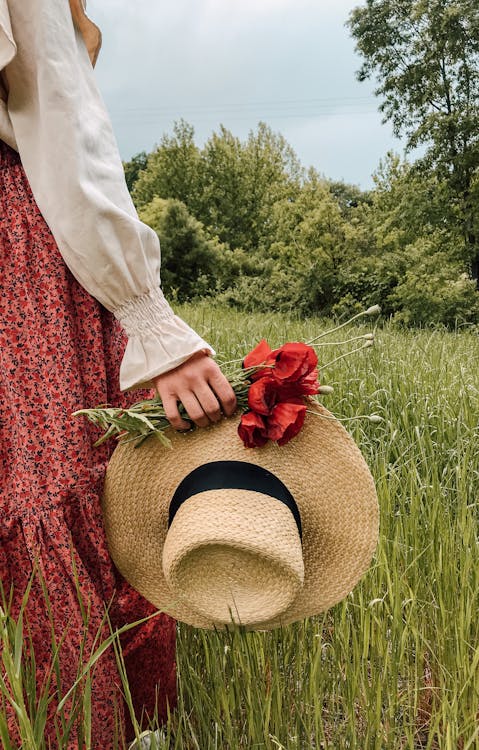 Woman with hat and flowers in field