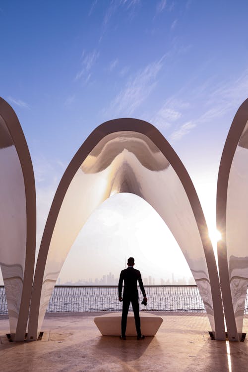 Man Standing under Futuristic Arches on a Promenade