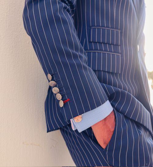 Free Close-up of a man in a pinstripe suit with his hand in his pocket, leaning against a wall. Stock Photo
