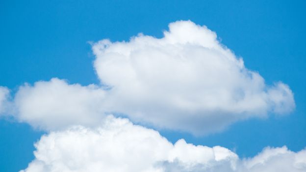 Serene cloudscape with fluffy white clouds against a vivid blue sky, ideal for nature themes.