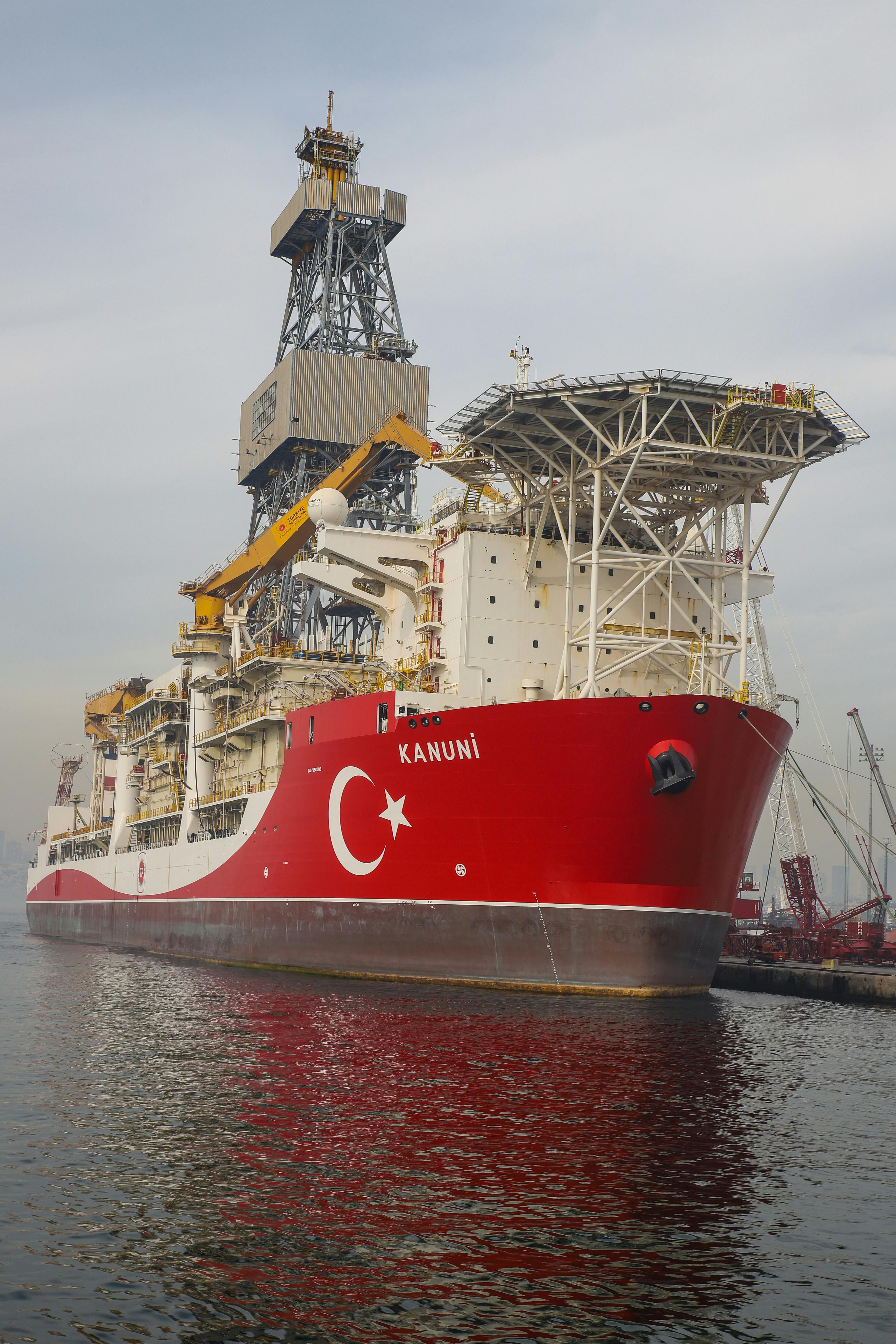 Free The Turkish drillship Kanuni is docked at a harbor, showcasing its vibrant red hull. Stock Photo