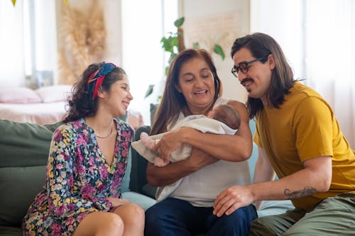 Free A Family Sitting on the Couch while Looking at the Baby Stock Photo
