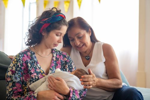 Free A heartwarming moment of two women embracing a newborn, symbolizing family love. Stock Photo