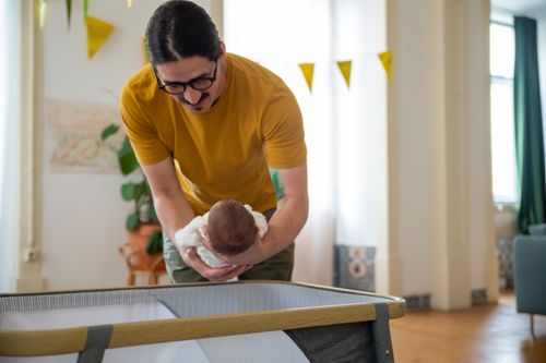 Free A loving father cradles his newborn in a cozy home setting, showcasing affection and family warmth. Stock Photo