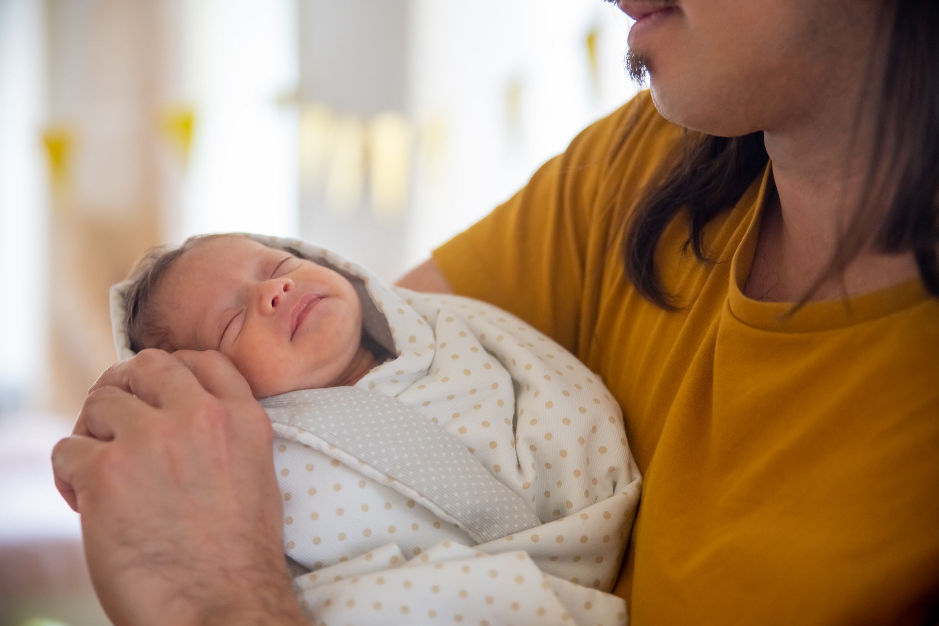 Father gently holding his premature baby inside a transparent skincubator