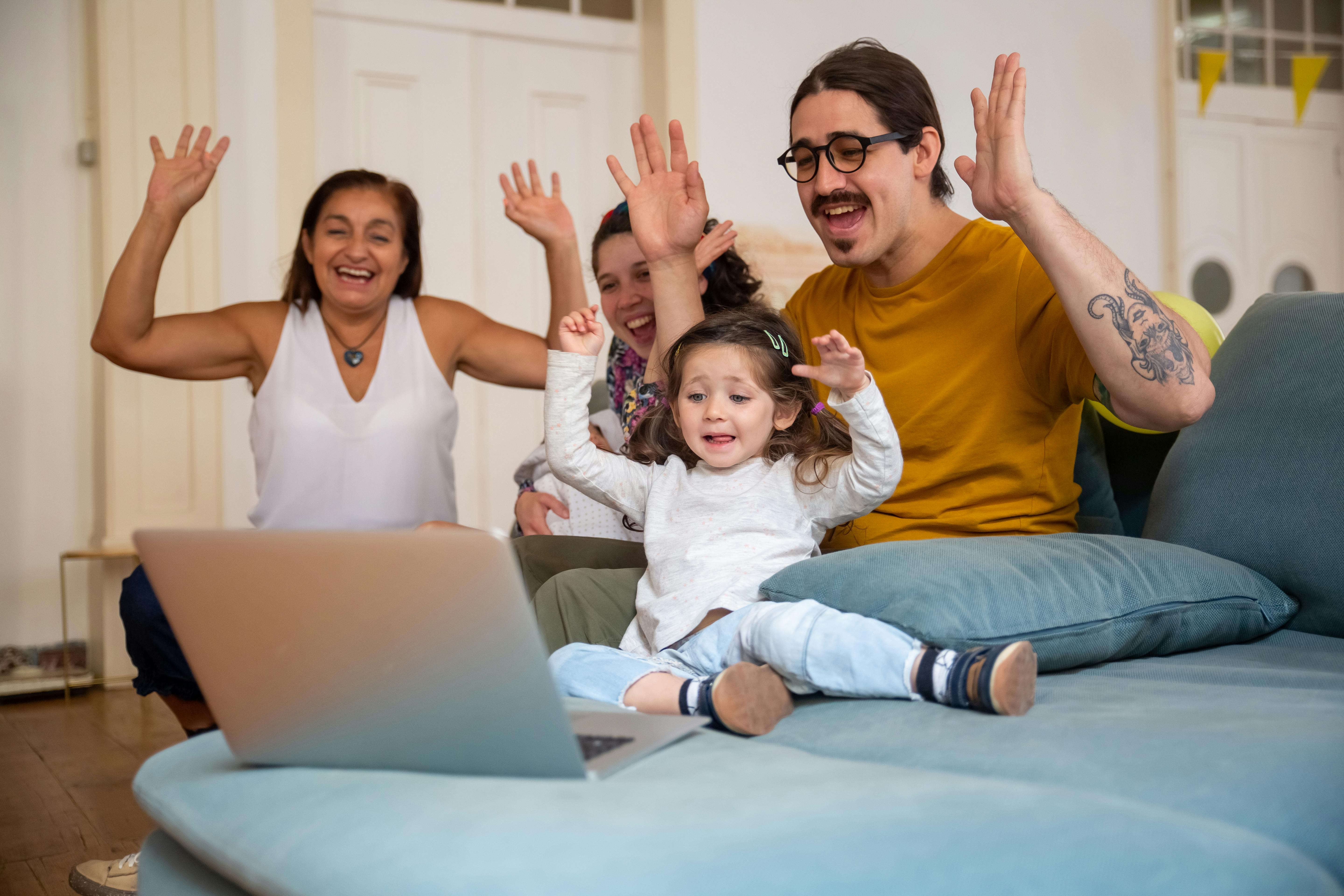 a happy family looking at the laptop while raising their hands together