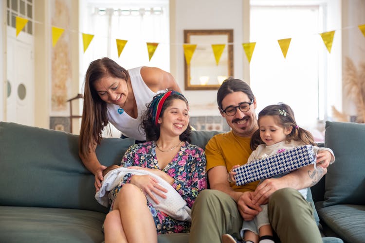 A Happy Family Sitting On The Couch While Having Conversation