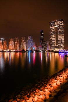 Explore this vibrant urban night scene with a beautifully lit skyline and tranquil water reflection.