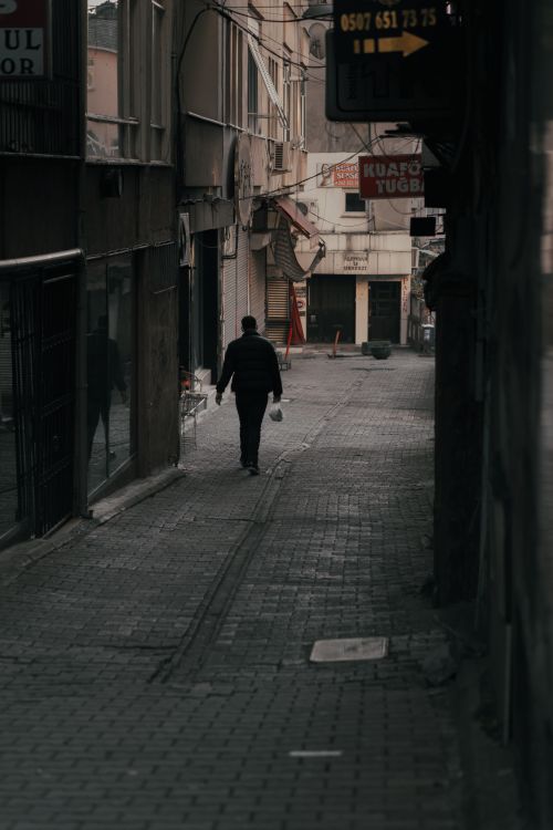 Free Man walking in a dimly lit alleyway in İzmit, Türkiye, creating a mysterious urban atmosphere. Stock Photo