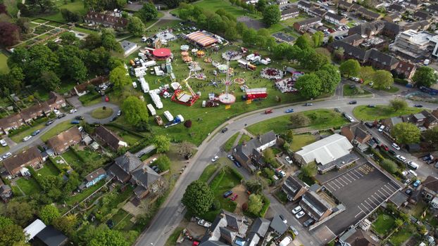 Aerial shot of a colorful funfair amidst green fields in Houghton Regis.